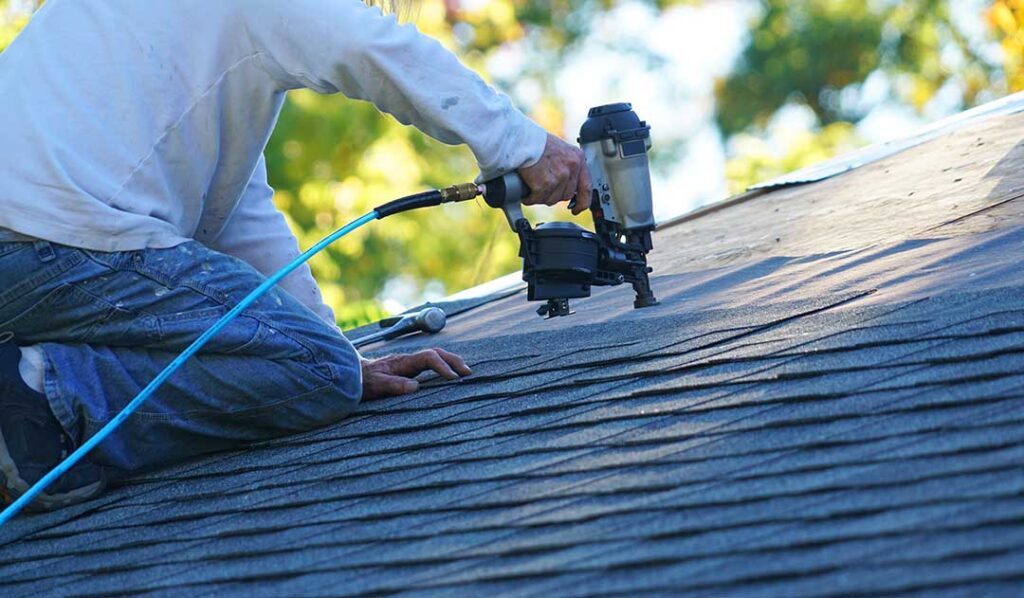 Homeowner using a roof rake to remove snow from a residential roof during winter.